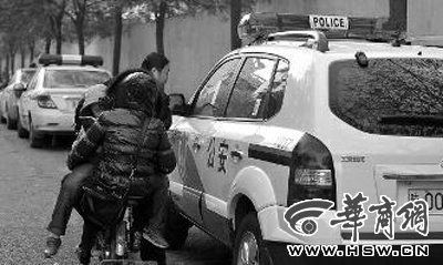 警车被贴上违停的罚单，骑车的路人觉得很好奇 本报记者 张杰 摄